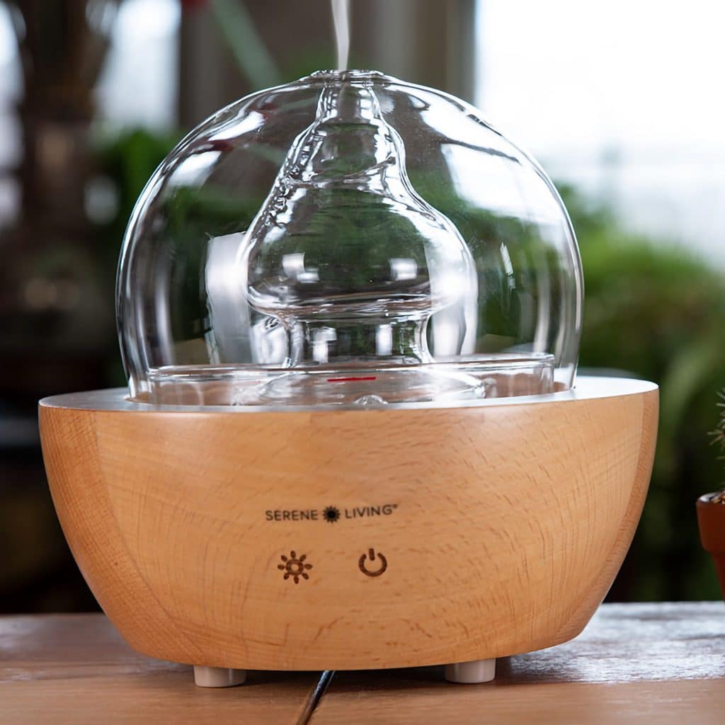 Fountain diffuser is crafted from hand blown glass and sustainably sourced wood for a stylish